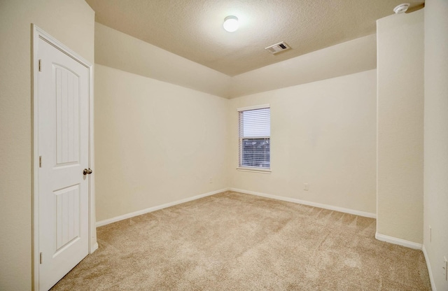 unfurnished room featuring a textured ceiling, light colored carpet, and vaulted ceiling