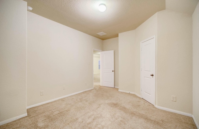 empty room with light colored carpet and a textured ceiling