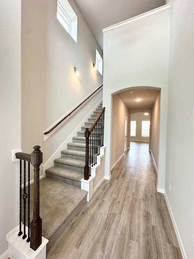 stairs with hardwood / wood-style floors and a towering ceiling