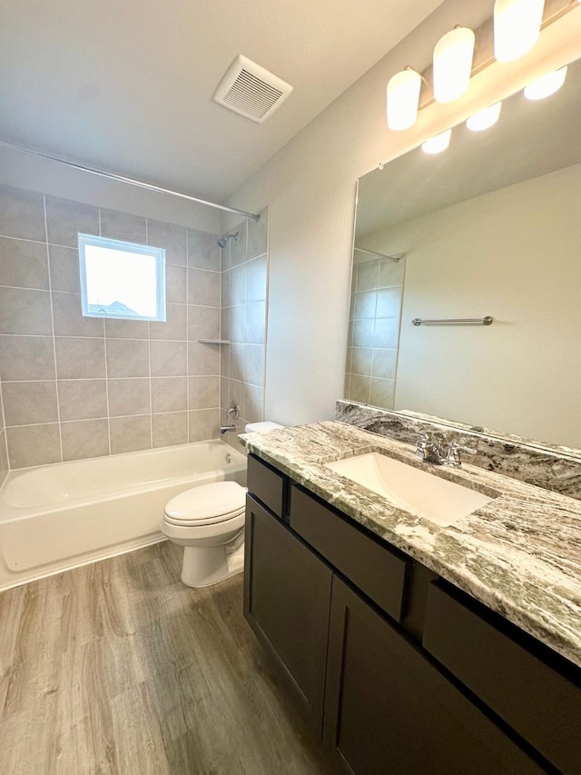 full bathroom featuring hardwood / wood-style floors, vanity, toilet, and tiled shower / bath