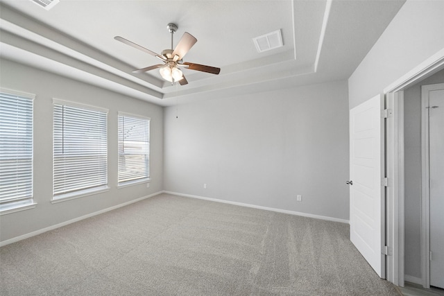 carpeted spare room with a tray ceiling and ceiling fan