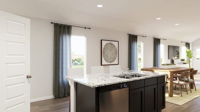 kitchen with light stone countertops, dishwasher, sink, dark hardwood / wood-style floors, and a center island with sink