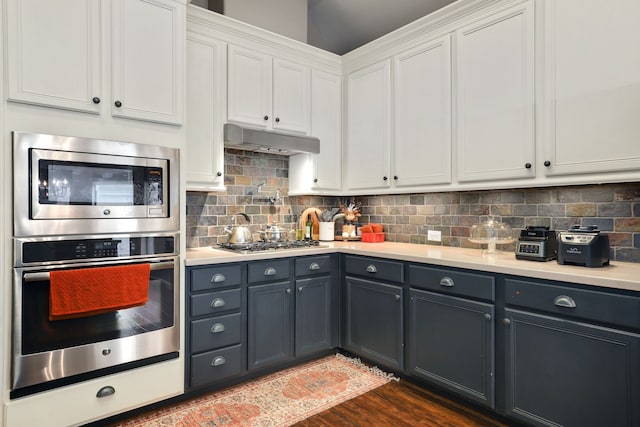 kitchen featuring backsplash, white cabinetry, stainless steel appliances, and dark wood-type flooring