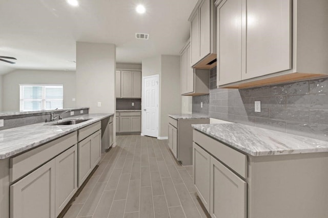 kitchen featuring tasteful backsplash, gray cabinetry, and sink