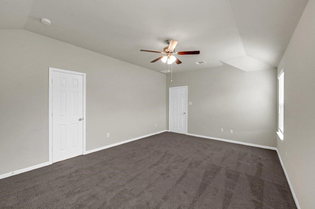 spare room featuring dark colored carpet, vaulted ceiling, and ceiling fan