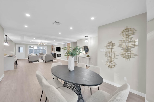 dining area with a raised ceiling and light wood-type flooring