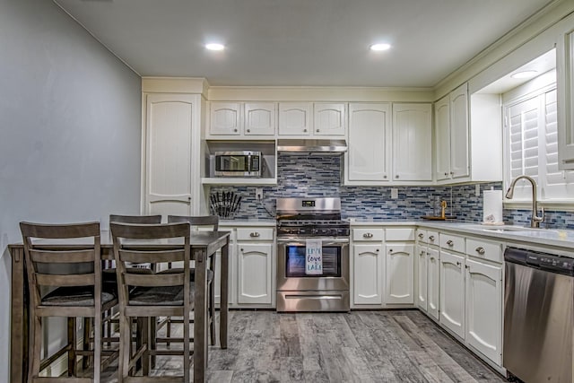 kitchen with white cabinetry, sink, light wood-type flooring, and appliances with stainless steel finishes