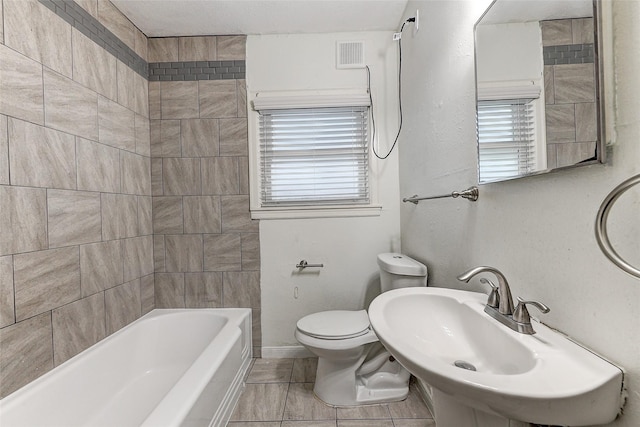 full bathroom featuring tile patterned floors, tiled shower / bath combo, toilet, and sink