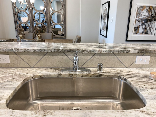 room details with light stone countertops, a notable chandelier, and sink