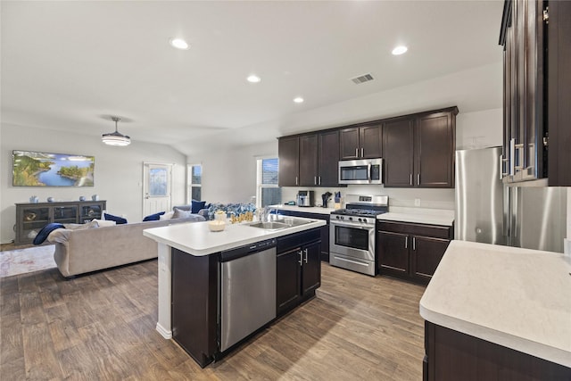 kitchen featuring appliances with stainless steel finishes, dark brown cabinets, a kitchen island with sink, sink, and hardwood / wood-style floors