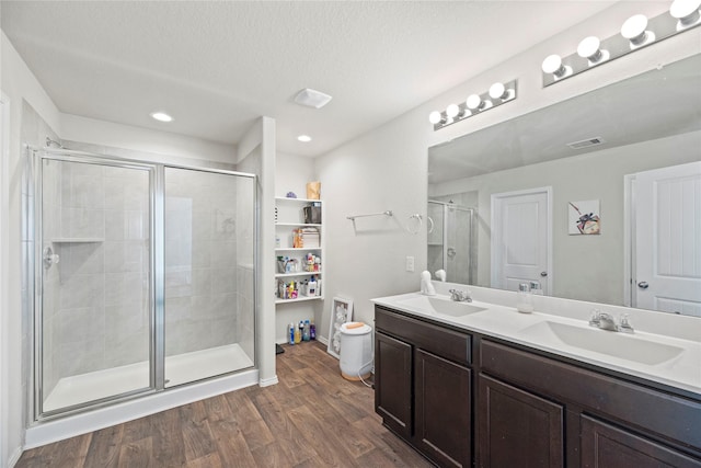 bathroom featuring a shower with shower door, wood-type flooring, a textured ceiling, and vanity