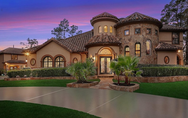 mediterranean / spanish-style house with a yard and french doors