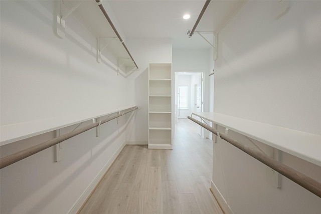 walk in closet with light hardwood / wood-style flooring