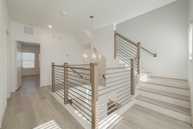 staircase featuring hardwood / wood-style flooring and an inviting chandelier