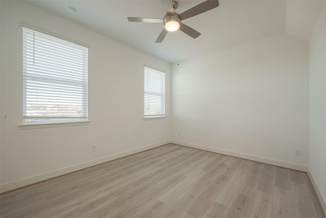 empty room with ceiling fan, vaulted ceiling, and light hardwood / wood-style flooring