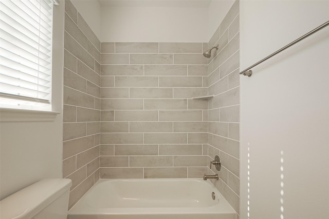 bathroom with toilet and tiled shower / bath