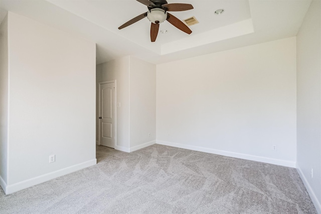 carpeted empty room featuring a tray ceiling and ceiling fan