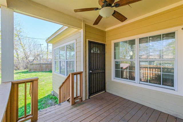 wooden deck featuring a lawn and ceiling fan