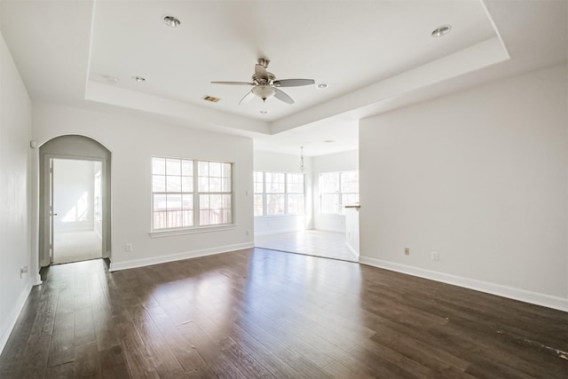 unfurnished room featuring dark hardwood / wood-style flooring, a tray ceiling, and ceiling fan