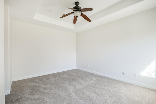 spare room with a tray ceiling, ceiling fan, and light colored carpet