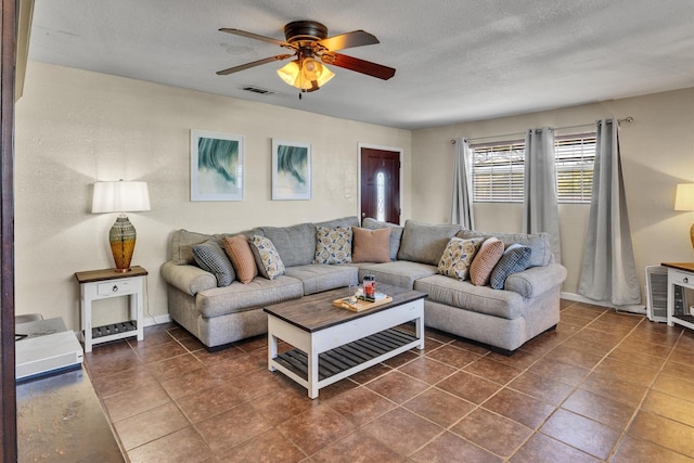 living room with a textured ceiling, dark tile patterned floors, and ceiling fan