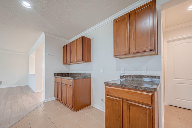 kitchen featuring a textured ceiling, crown molding, and light tile patterned flooring