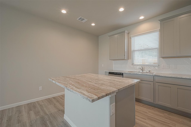 kitchen featuring gray cabinetry, a center island, light wood-type flooring, and sink