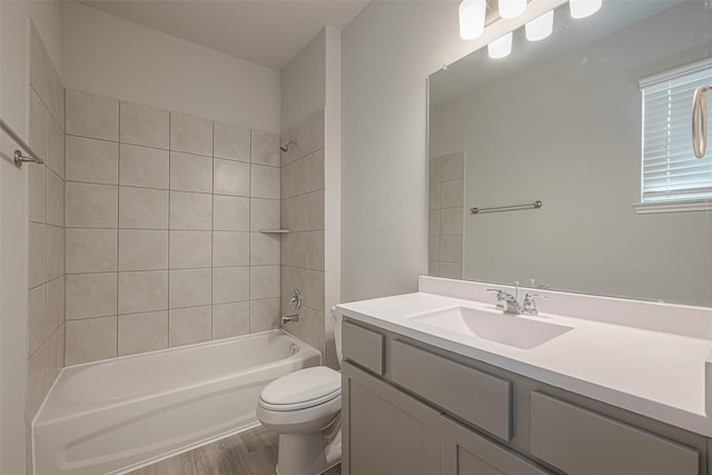 full bathroom featuring hardwood / wood-style floors, vanity, toilet, and tiled shower / bath