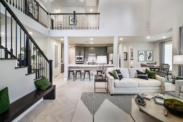 living room with recessed lighting, visible vents, stairway, and a high ceiling