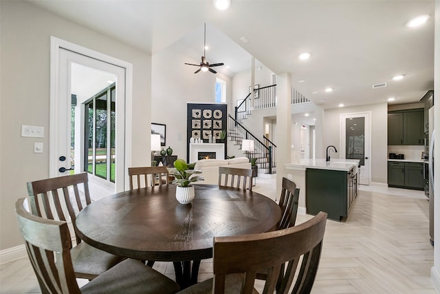 dining room with a lit fireplace, stairway, baseboards, and recessed lighting