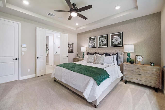 bedroom featuring light carpet, visible vents, baseboards, a raised ceiling, and wallpapered walls