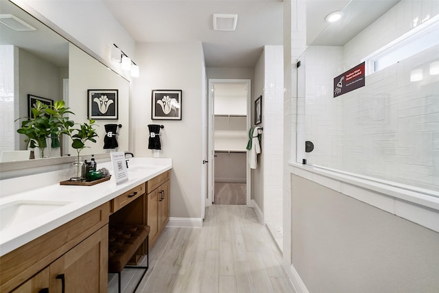 bathroom with wood finished floors, visible vents, a spacious closet, and a walk in shower