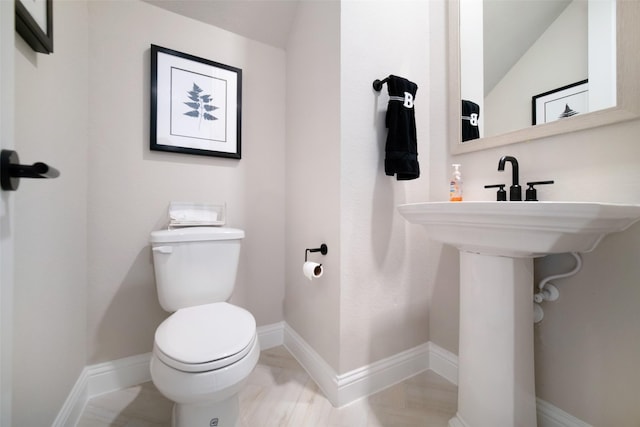 bathroom with toilet, baseboards, and lofted ceiling