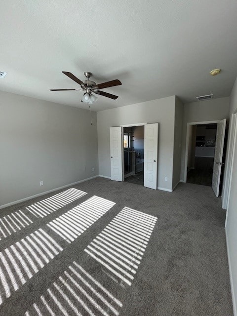 unfurnished bedroom featuring dark colored carpet and ceiling fan