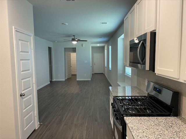 kitchen featuring ceiling fan, light stone counters, appliances with stainless steel finishes, dark hardwood / wood-style flooring, and white cabinetry