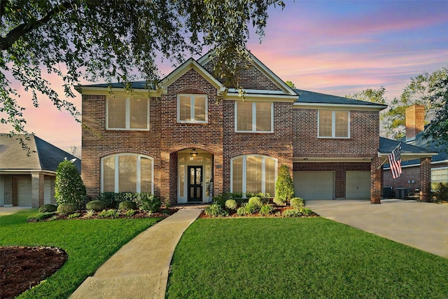 view of front of home featuring a lawn, a garage, and central air condition unit