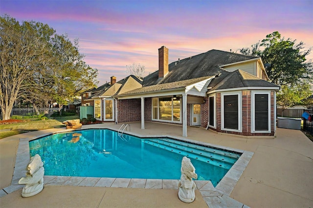 pool at dusk featuring a patio area