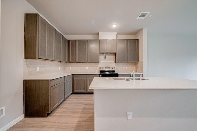 kitchen with electric range, light wood-type flooring, and sink