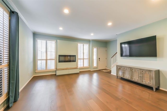 unfurnished living room with hardwood / wood-style flooring and crown molding