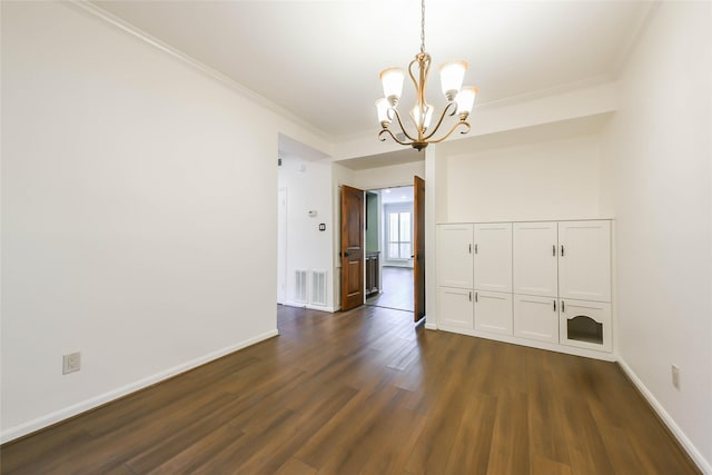 empty room featuring dark hardwood / wood-style flooring, an inviting chandelier, and ornamental molding