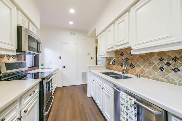 kitchen with appliances with stainless steel finishes, backsplash, dark wood-type flooring, sink, and white cabinets