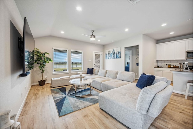 living room featuring ceiling fan, light wood-type flooring, and vaulted ceiling