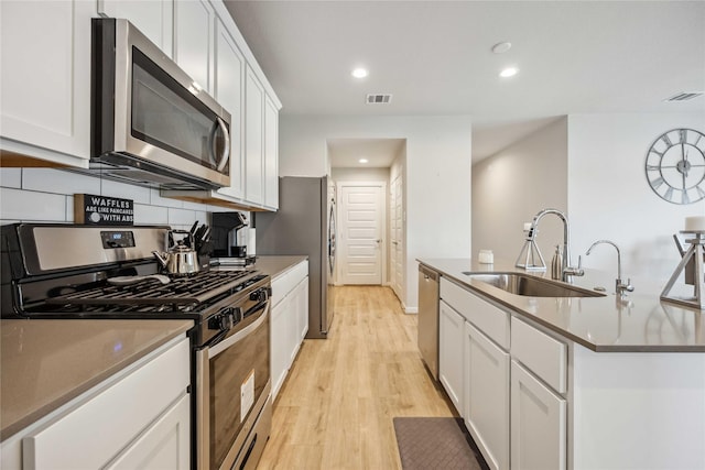 kitchen featuring white cabinets, appliances with stainless steel finishes, an island with sink, and sink