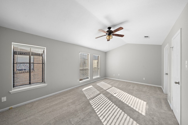 unfurnished bedroom featuring ceiling fan, light colored carpet, multiple windows, and vaulted ceiling