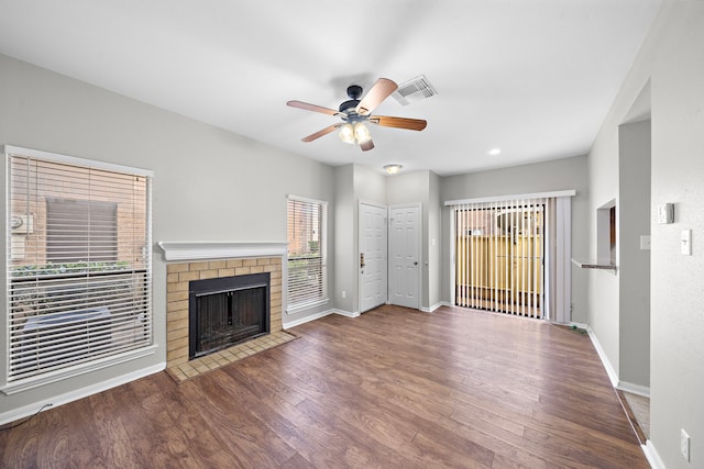 unfurnished living room with ceiling fan, a fireplace, and dark wood-type flooring