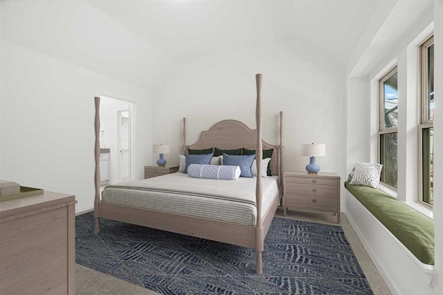 carpeted bedroom with vaulted ceiling, connected bathroom, and multiple windows