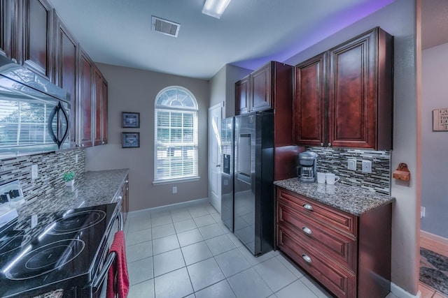 kitchen featuring backsplash, black range with electric stovetop, stainless steel fridge, dark stone countertops, and light tile patterned flooring