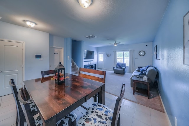 dining space with ceiling fan, light colored carpet, and a textured ceiling