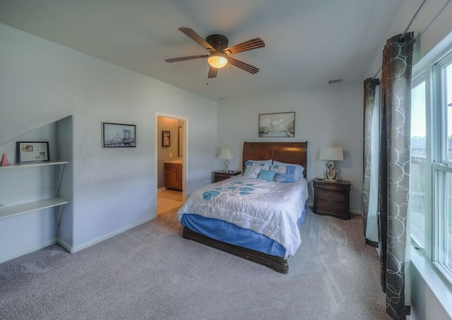 carpeted bedroom with ensuite bath and ceiling fan