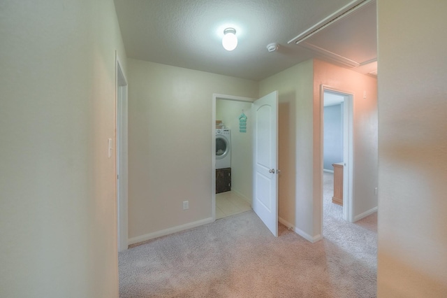 interior space featuring washer / clothes dryer, light colored carpet, and a textured ceiling